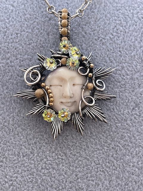 Necklace of carved moon bone in Sterling silver with Swarovski flowers, by Judy Dailey